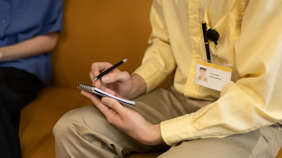 Caregiver communication log: how to track updates from doctors, aides, and family Person with badge taking notes in a notebook