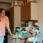 Caregiver helping an older woman use a walker at home