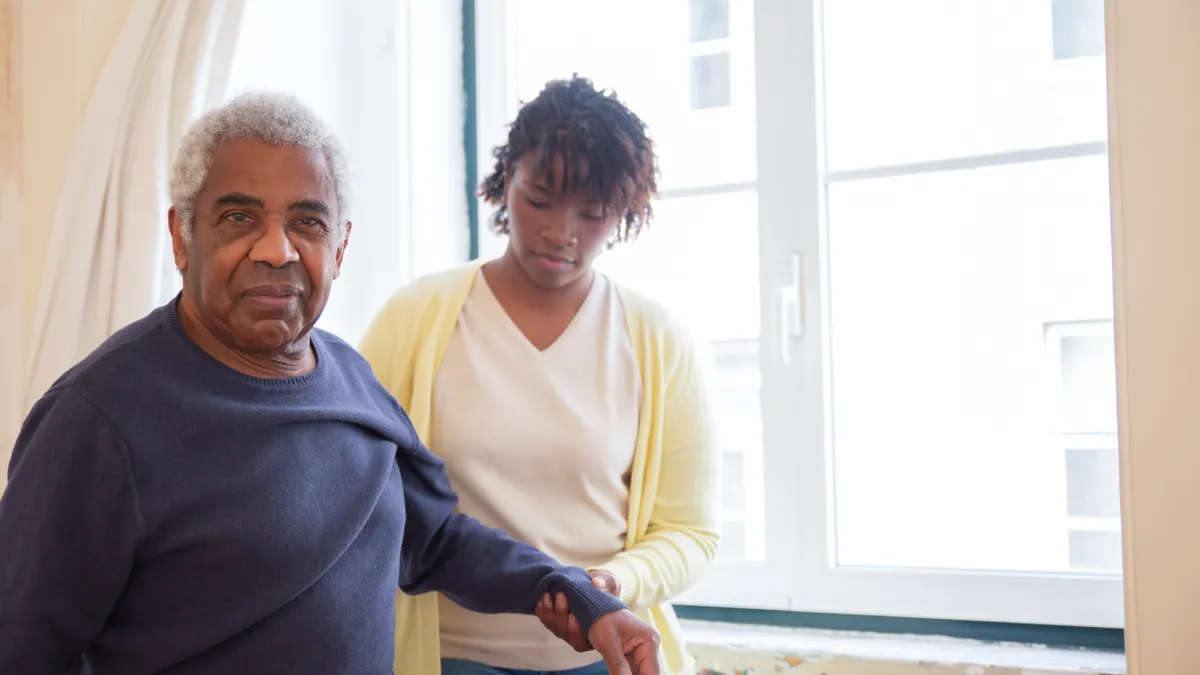 Caregiver home safety and daily living — The Complete Guide Caregiver supporting an older man standing indoors