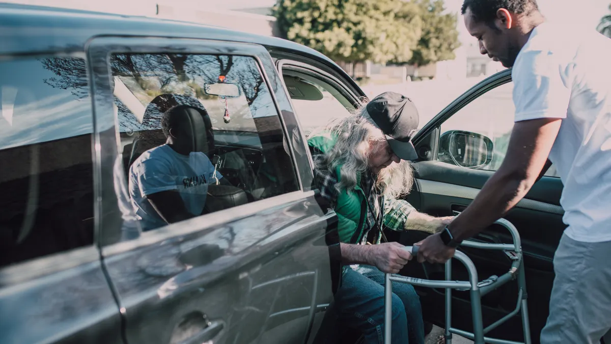 Caregiver home safety and daily living — The Complete Guide Caregiver assisting an older adult into a car with a walker