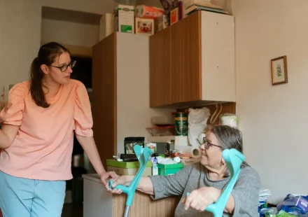 Caregiver helping an older woman use a walker at home