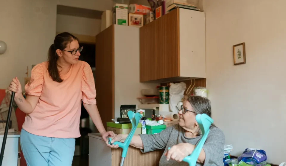 Caregiver helping an older woman use a walker at home