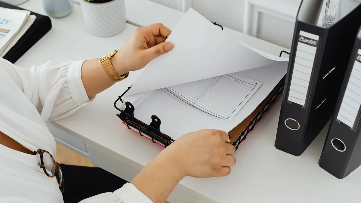 Caregiver paperwork: which legal and medical documents to keep together Person filing papers into a binder