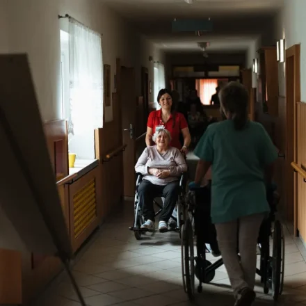 Caregiver pushing a wheelchair through a hallway