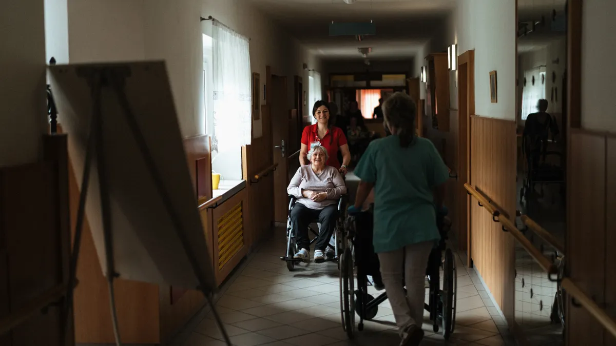 Caregiver pushing a wheelchair through a hallway