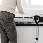 Older adult at a bathroom sink with a walker nearby