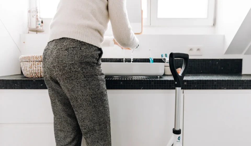 Older adult at a bathroom sink with a walker nearby