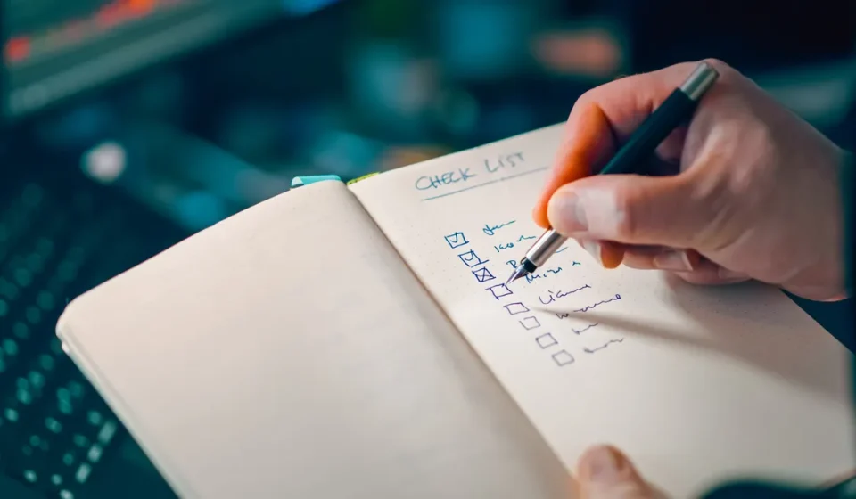 Hand ticking a checklist in a notebook