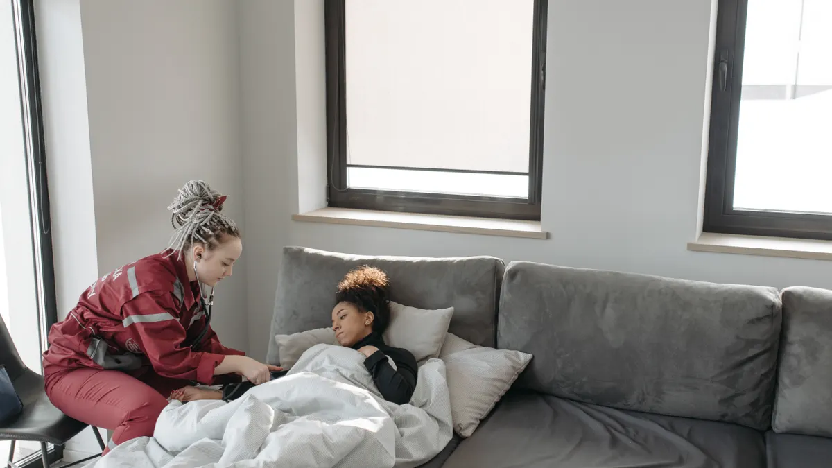 Caregiver beside a patient resting on a couch at home