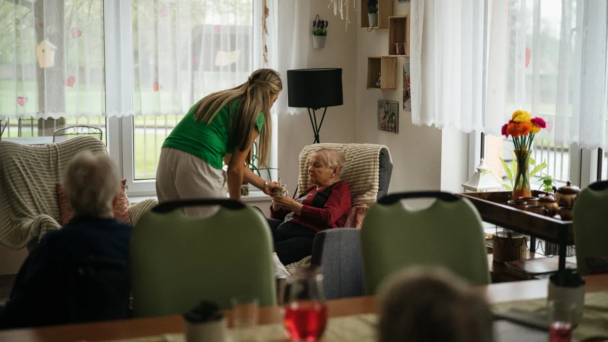 Caregiver helping an elderly woman in a living room