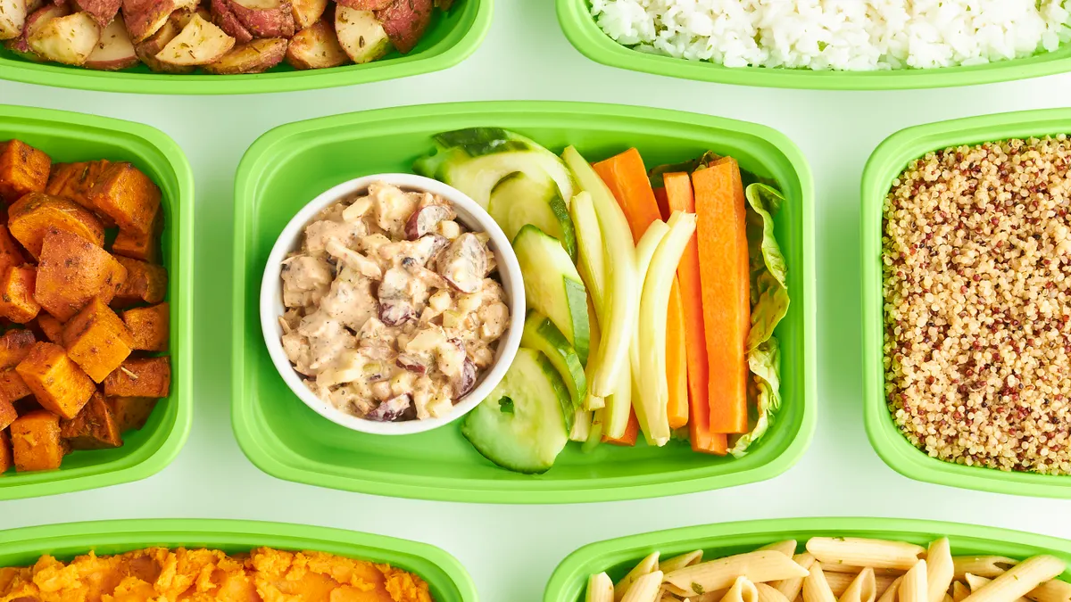 Colorful meal-prep containers with vegetables, grains, and dip